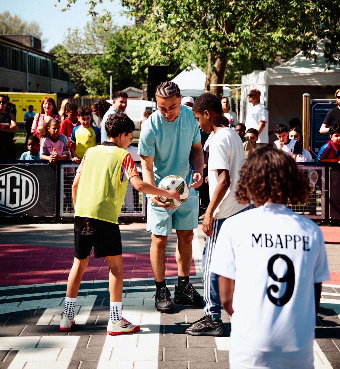 Sergiño Dest holding a soccer ball with two young boys at the Almere court