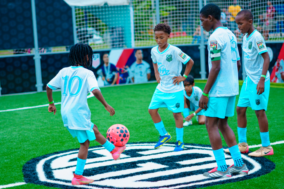 Young players in light blue jerseys playing on the Sergiño Dest Court