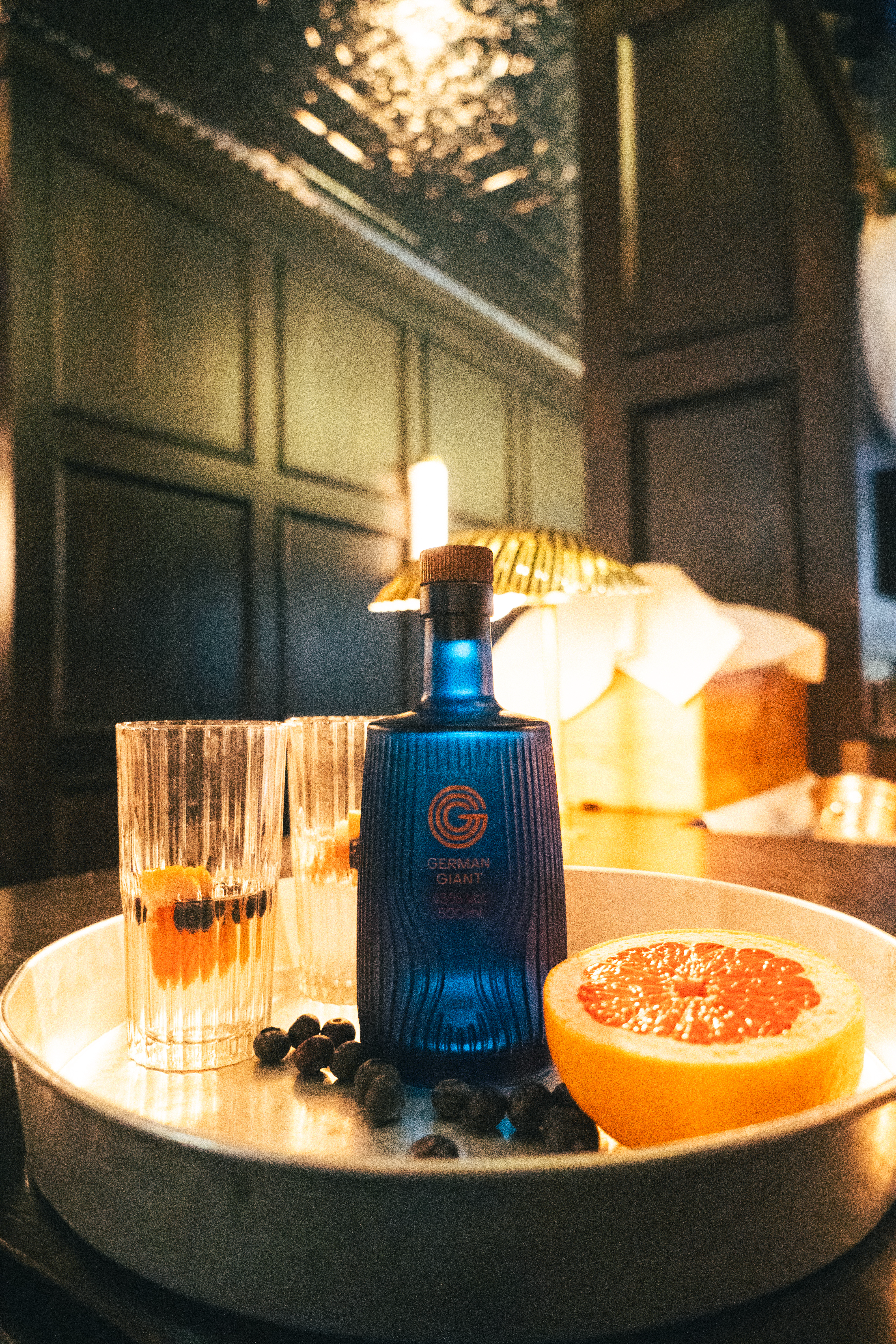 A bottle of German Giant Gin on a tray with glasses and citrus