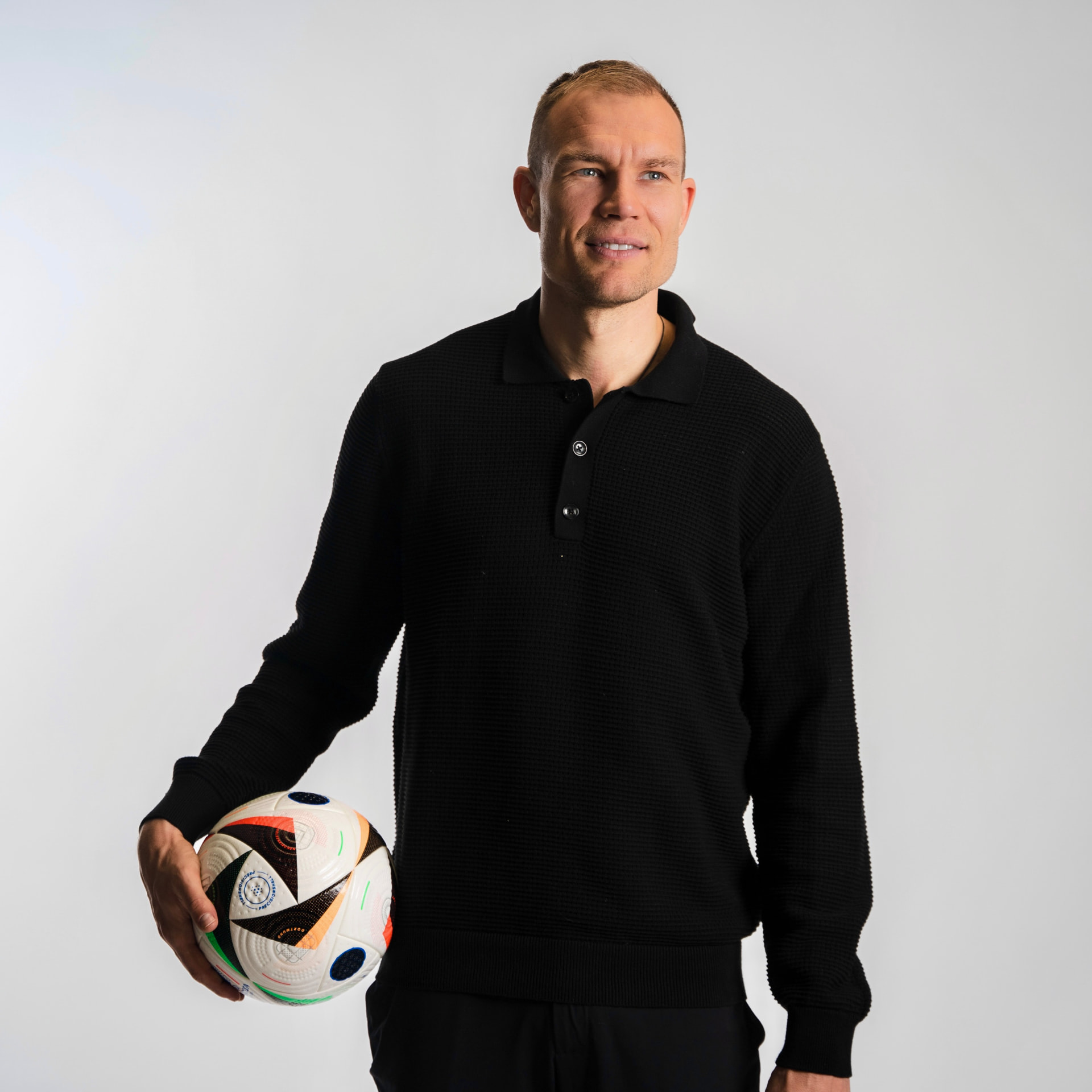 Holger Badstuber holding a football in a black polo shirt